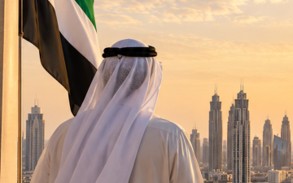 UAE flag overlooking the modern Dubai skyline, representing unity and the foundations of national development.